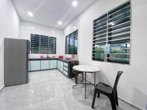 a kitchen with a table and chairs and windows at 79 Village in Muar
