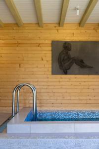 a bath tub with a statue of a man on a wall at Kalna Smīžu pirtiņa in Melturi
