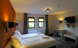 a hotel room with a bed and a television at Hotel Bi-j Ons in Lichtenvoorde