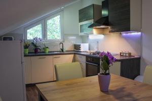a kitchen with a wooden table with a vase of flowers on it at Apartman Nadja&Dani in Kulen Vakuf