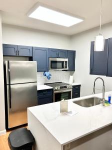 Una cocina con gabinetes azules y un refrigerador de acero inoxidable. en Dallas Modern Apt, en Dallas