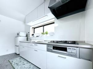 a white kitchen with a stove and a refrigerator at guesthouse大阪城 in Osaka +25 photos