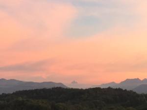 a sunset over a mountain range with trees in the foreground at Poulou Pyrénées in Gelos
