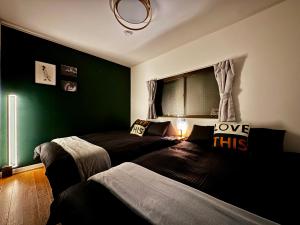 two beds in a bedroom with green walls at guesthouse大阪城 in Osaka
