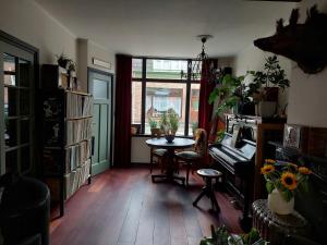 a living room with a table and a piano at Onthaast & Geniet in Den Helder