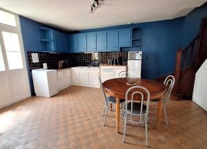een keuken met blauwe muren en een houten tafel en stoelen bij La Maison Douessine - Hyper Centre Doué La Fontaine - WIFI gratuit -Proche Bioparc Zoo in Doué-la-Fontaine