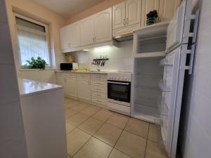 a white kitchen with white cabinets and a refrigerator at József Attila Apartman Hajdúszoboszló in Hajdúszoboszló