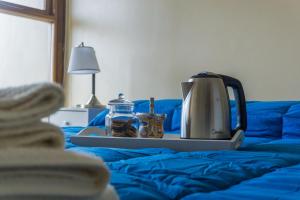 a tray with a tea kettle and two jars on a bed at Gente del Sur - Odino in Ushuaia
