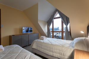a bedroom with two beds and a tv on a cabinet at Gente del Sur - Odino in Ushuaia