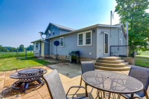 Un patio con mesa y sillas y una casa. en Ohio Farmhouse Retreat with Fire Pit and Patio, en Monroeville
