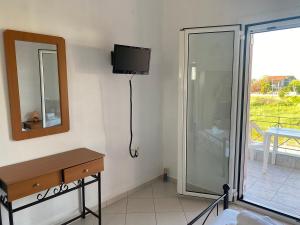 a bathroom with a mirror and a tv and a glass door at Pefki Apartment 6 in Artemísion