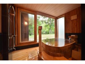 una gran bañera de madera en una habitación con ventana en La Vista Akangawa, en Akankohan