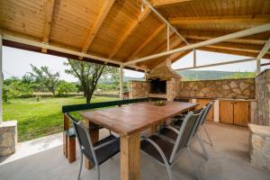 an outdoor dining room with a wooden table and chairs at Holiday House Ivan with heated pool in Neorić