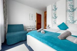 a white bedroom with a blue bed and a chair at Manna Villa in Balatonfüred