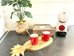due tazze rosse su un tagliere accanto a un frullatore di Logement paisible jacuzzi jardin privatif climatisation a Baie-Mahault