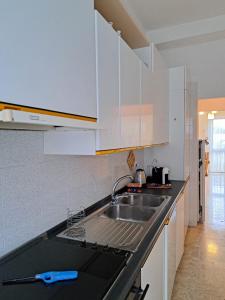 Una cocina con gabinetes blancos y un fregadero. en Casa Lea, en Taranto