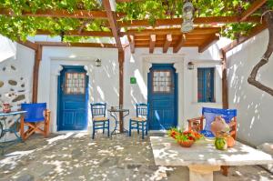 un patio con puertas y sillas azules y una mesa. en Venetiko Apartments, en Naxos Chora