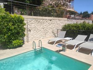 a swimming pool with chairs and a rock wall at Plus Belle La Vue Allauch in Allauch