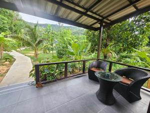 a balcony with a table and chairs and a view of a forest at Bang Po Hut in Ban Bang Po