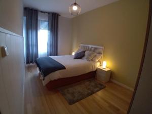 a bedroom with a bed with a lamp and a window at Acogedor piso en Maliaño in Camargo