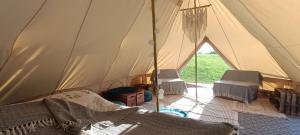 MiłkiMiła Łąka Glamping的帐篷配有两把椅子和一张沙发