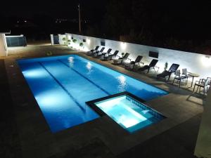 a swimming pool at night with chairs and a table at Villa XY in Blagaj +45 photos