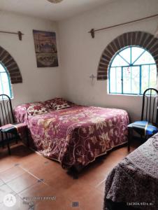 a bedroom with two beds and two windows at Casa Ecológica Pablo in Curva La Pera