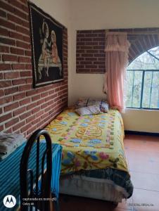 a bed in a room with a brick wall at Casa Ecológica Pablo in Curva La Pera