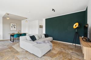 un salon avec un canapé blanc et un mur vert dans l'établissement Ferienhaus-Terrassen-Parkplatz, à Cobourg