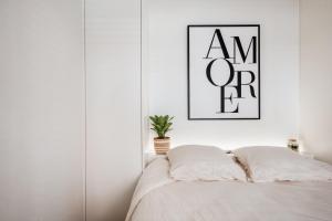 a white bedroom with a bed with a picture on the wall at Sejoylia Knokke: app 2ch luxueux au centre de KH in Knokke-Heist