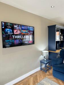 a living room with a blue couch and a tv on the wall at Victoria Cottage, Cullercoats in Cullercoats