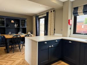a kitchen with black cabinets and a dining table at Victoria Cottage, Cullercoats in Cullercoats