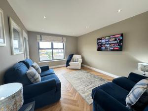 a living room with two blue couches and a tv at Victoria Cottage, Cullercoats in Cullercoats