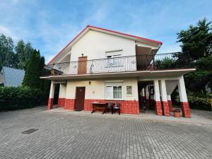 a white and red house with a balcony and a table at VILLA BIAŁA in Okuninka