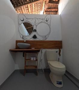 a bathroom with a toilet and a mask on the wall at C U Hostel in Trincomalee