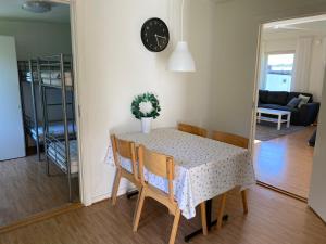 a dining room table with chairs and a clock on the wall at Hällestrand Vandrarhem - Lägenhet "Laxen" in Strömstad