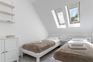 two beds in a white room with two windows at Morze Ciszy in Dziwnów