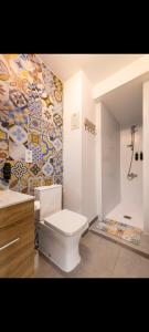 a bathroom with a toilet and a mosaic wall at Alojamiento el halcon in Santoña