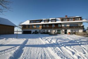 a large building in the snow with footprints in the snow at Ohmayerhof in Isny im Allgäu