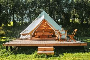 MiłkiMiła Łąka Glamping的木制甲板上的帐篷,配有一张床