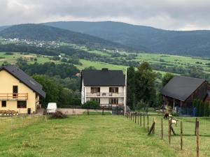 a house on a hill with a field and a fence at Agroturystyka Zagroda Miłkowskie in Słopnice