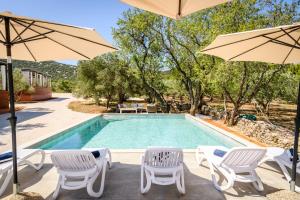 a swimming pool with two chairs and umbrellas at Luxury and Cosy Little House Ivinj 1 in Tisno