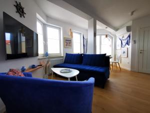 a living room with a blue couch and a table at Aravell E23 Darłówko Wschodnie in Darlowko