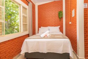 un lit dans une chambre avec un mur de briques dans l'établissement Rancho Colonial 6 suítes acesso ao Lago das Brisas, à Corumbazul