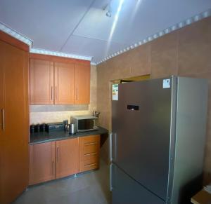 a kitchen with a stainless steel refrigerator and wooden cabinets at Buffalo guest lodge in Bushbuckridge