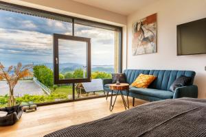 a bedroom with a blue couch and a large window at Hotel Frost in Maribor