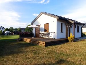 a small white house with a wooden deck at Domek agroturystyczny in Zawada