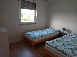 two beds in a room with a window at Domek agroturystyczny in Zawada