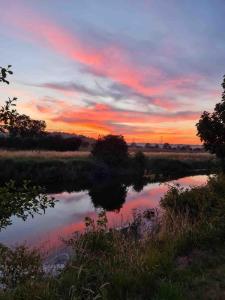 a sunset over a pond in a field at Dutch Cruiser Ship on a Tranquil Secluded River in Tonbridge