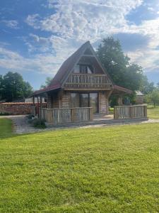 a large log cabin with a large grass field at Auci Guest house 1 in Liepāja